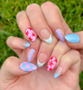 Hand-Painted press-on nails with various bright designs in red, light pink, and light blue colors. The press-on nail designs include stars, blueberries, dots, and checkers.