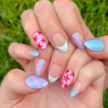 Hand-Painted press-on nails with various bright designs in red, light pink, and light blue colors. The press-on nail designs include stars, blueberries, dots, and checkers. 