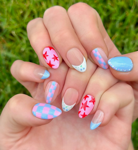 Hand-Painted press-on nails with various bright designs in red, light pink, and light blue colors. The press-on nail designs include stars, blueberries, dots, and checkers. 