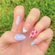 Colorful nail art with stars, checkers, and blueberries. Nail colors include light blue, red, and light pink.
