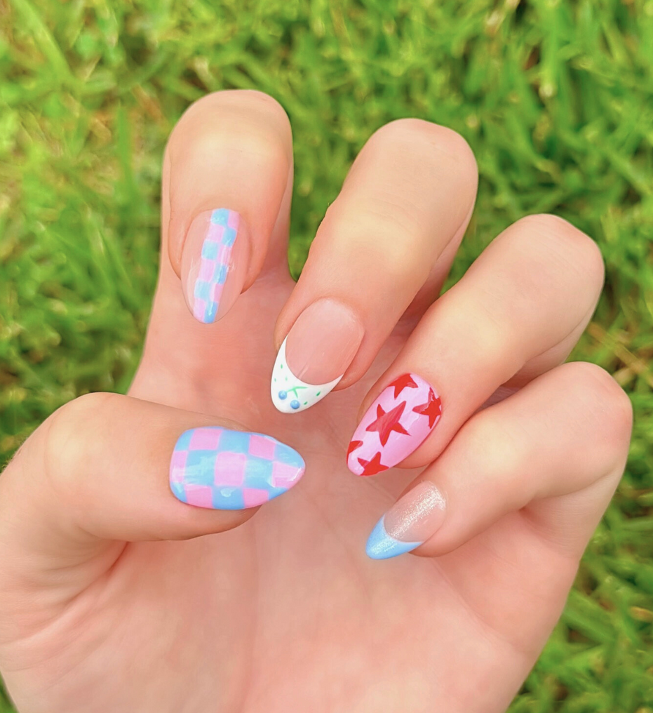 Colorful nail art with stars, checkers, and blueberries. Nail colors include light blue, red, and light pink.
