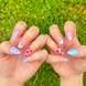 Hand-Painted press-on nails with various colorful, bright nail art in red, light pink, and light blue colors. The press-on nail designs include stars, blueberries, dots, and checkers. 