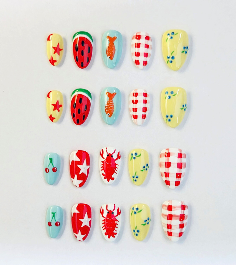 Summer press on nails with vibrant, fun designs. Nail designs include a lobster, stars, cherries, gingham, fish, watermelon, and blueberries. Nail colors include red, white, orange, light blue, green, and yellow. 24 Piece press ons are displayed on a white background