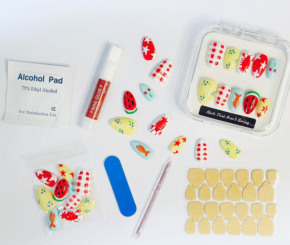 Nail art kit for NTAB Lobster Boil summer press on nails Nail kit includes 24 piece press on nails, cuticle stick, nail file, adhesive tabs, alcohol pad, and nail glue. All nail kit contents are displayed on a white background.
