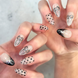 Two hands showing nails with hand painted salon press-on nails in long almond shape, featuring black and silver polka dots, bows, and french tips with silver bows on neutral background