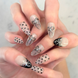 Two hands interlocked showing hand painted luxury press-on nails in long almond shape, featuring black and silver polka dots, bows, and french tips