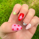 Hand-Painted acrylic press-on nails with vibrant colors and designs including strawberries, stars, gingham, zebra print, and french tips. The nail colors are red, light green, light pink, zebra print, and silver details. The hand is displayed on a grass background.