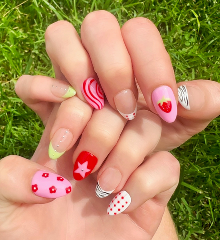 Hand-Painted acrylic press-on nails with vibrant colors and designs including strawberries, stars, gingham, zebra print, and french tips. The nail colors are red, light green, light pink, zebra print, and silver details.