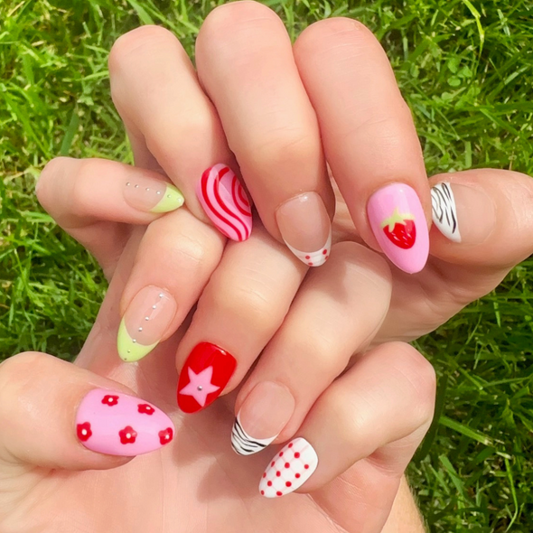 Hand-Painted acrylic press-on nails with vibrant colors and designs including strawberries, stars, gingham, zebra print, and french tips. The nail colors are red, light green, light pink, zebra print, and silver details.