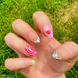 Hand-Painted acrylic press-on nails with vibrant colors and designs including strawberries, stars, gingham, zebra print, and french tips. The nail colors are red, light green, light pink, zebra print, and silver details. One hand displaying nails is on a grassy summer background.